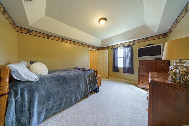 bedroom with a tray ceiling, light carpet, a textured ceiling, and baseboards