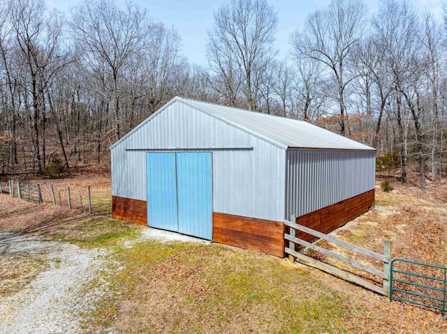 view of pole building with driveway and fence