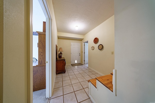 interior space featuring light tile patterned floors, a textured ceiling, and baseboards