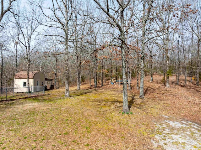 view of yard featuring a wooded view and fence