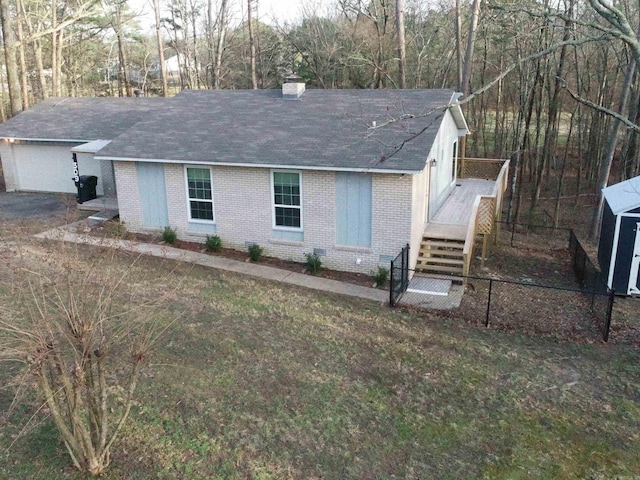 single story home featuring a front lawn, fence, brick siding, and roof with shingles