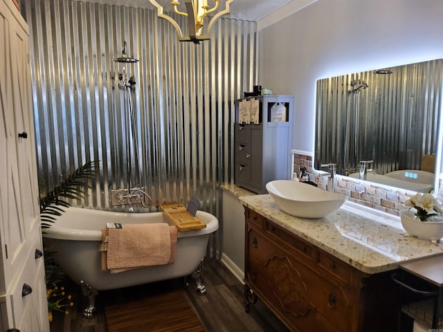 bathroom with a freestanding tub, wood finished floors, an inviting chandelier, decorative backsplash, and vanity