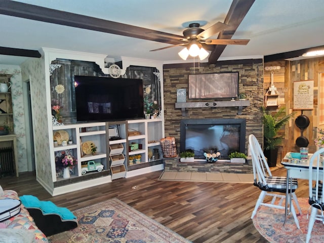 living room with a stone fireplace, crown molding, a ceiling fan, and wood finished floors