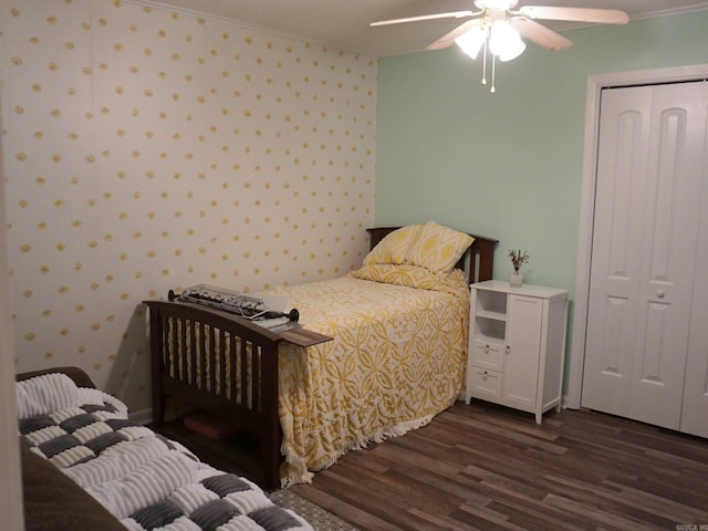 bedroom featuring a ceiling fan, wallpapered walls, dark wood-style flooring, ornamental molding, and a closet