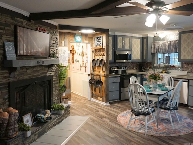 dining room featuring beam ceiling, light wood-style flooring, a fireplace, and ceiling fan