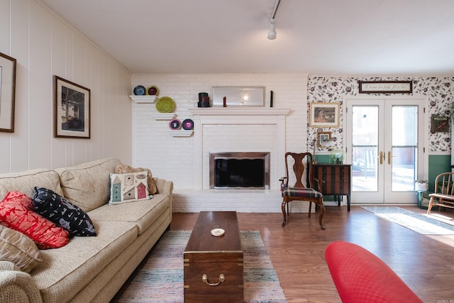 living area featuring a fireplace, wood finished floors, rail lighting, and french doors