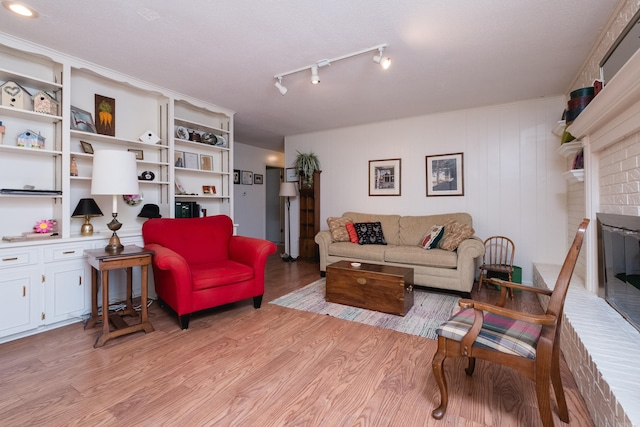 living room with a brick fireplace and light wood-type flooring