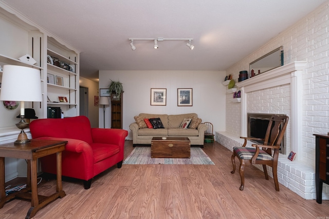 living area with a brick fireplace and wood finished floors