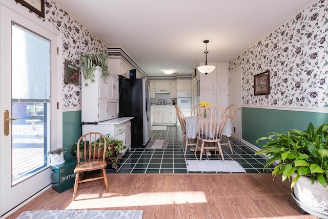 dining area with wallpapered walls, plenty of natural light, and a wainscoted wall