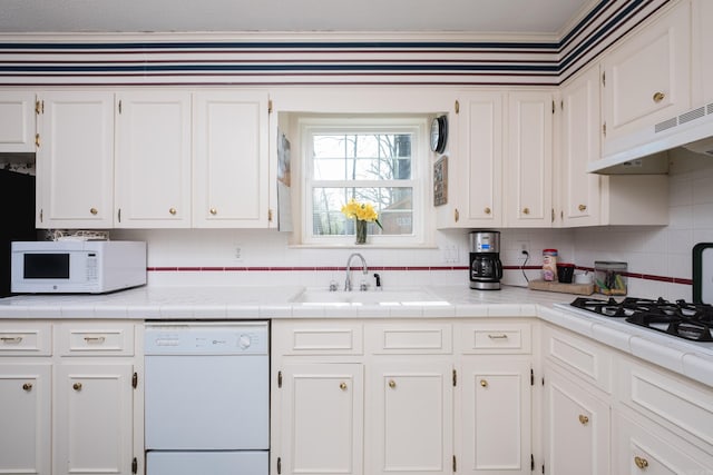 kitchen with under cabinet range hood, white appliances, white cabinetry, and a sink