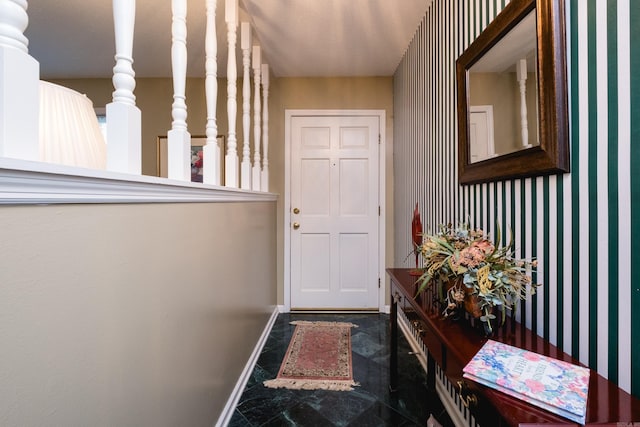 doorway with wallpapered walls and baseboards