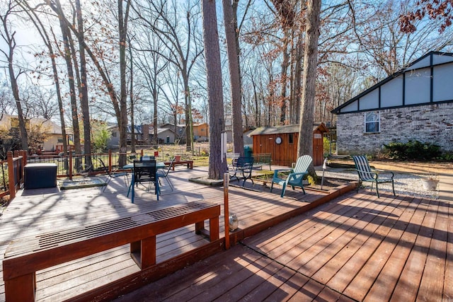 wooden terrace featuring a storage unit, a residential view, an outdoor structure, and outdoor dining space