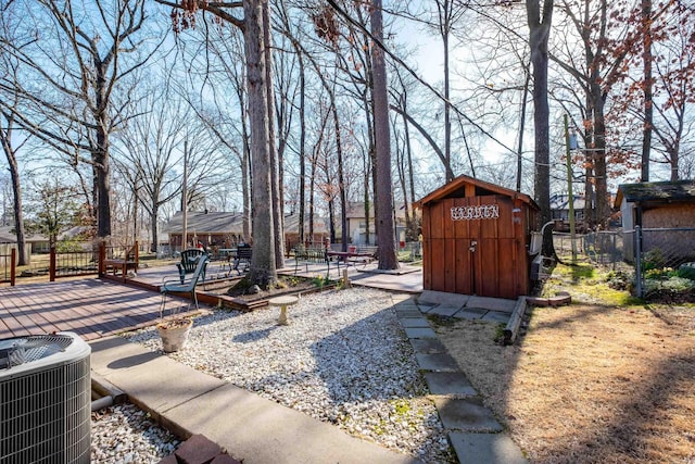 view of yard featuring a shed, an outdoor structure, central AC, and fence