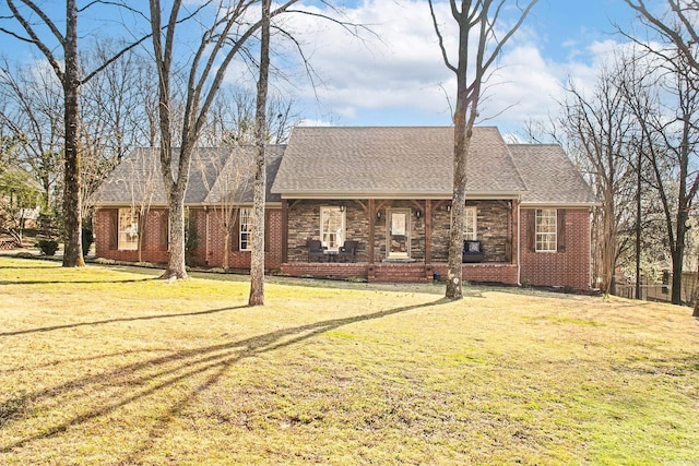 view of front facade with brick siding, a front lawn, and roof with shingles