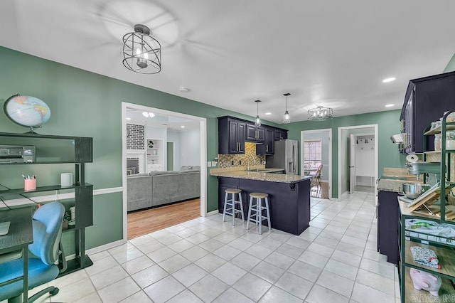 kitchen with tasteful backsplash, a breakfast bar, light tile patterned floors, a peninsula, and stainless steel refrigerator with ice dispenser