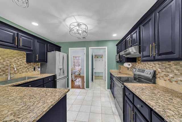 kitchen featuring a sink, under cabinet range hood, appliances with stainless steel finishes, light tile patterned floors, and baseboards