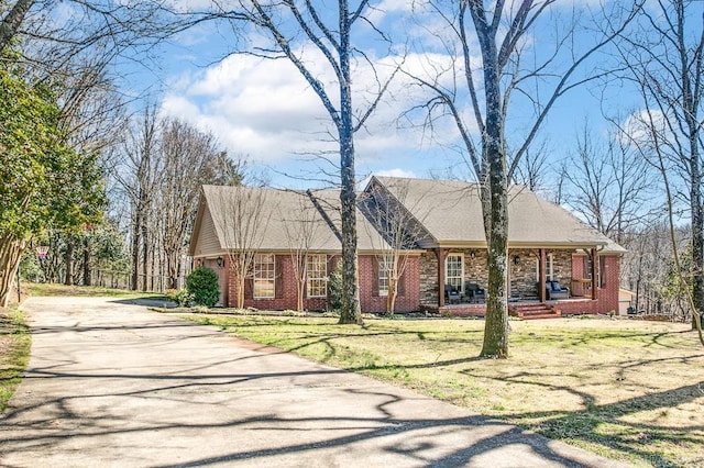 cape cod home with brick siding, covered porch, and a front yard