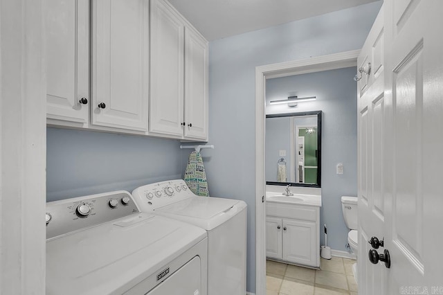 clothes washing area featuring a sink, cabinet space, light tile patterned floors, and washing machine and clothes dryer