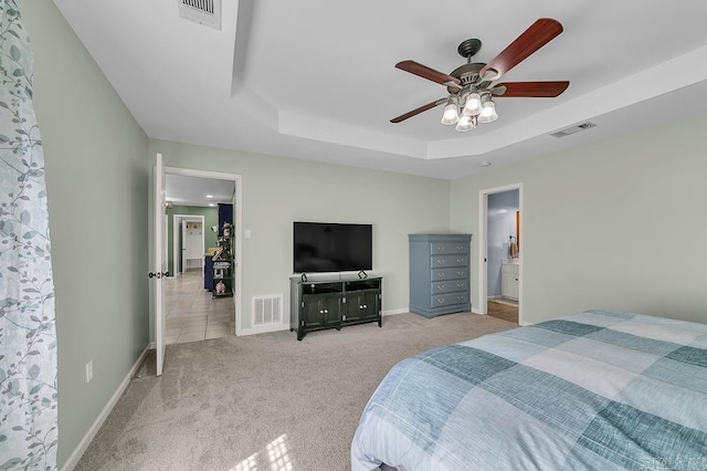 bedroom featuring visible vents, light colored carpet, and a tray ceiling