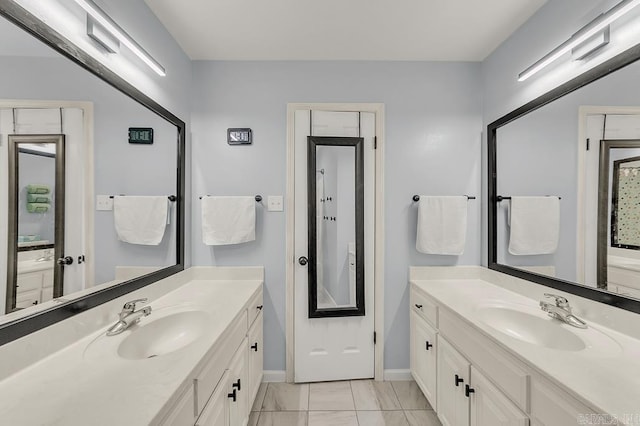 bathroom with two vanities, baseboards, and a sink