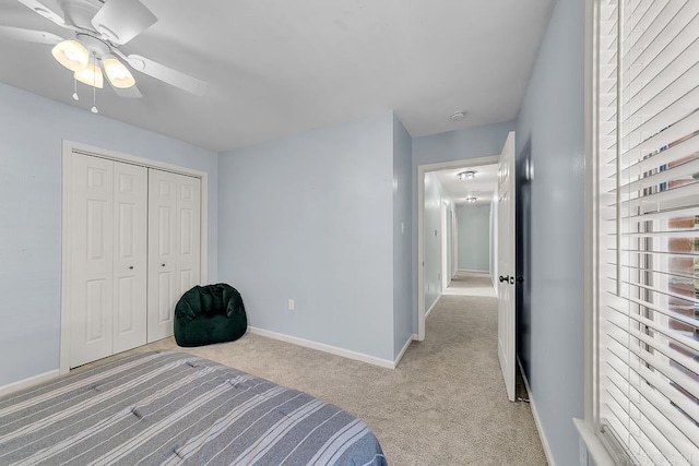 bedroom featuring a ceiling fan, baseboards, a closet, and light carpet