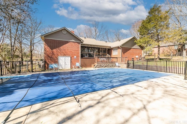 community pool with a patio area, a deck, and fence