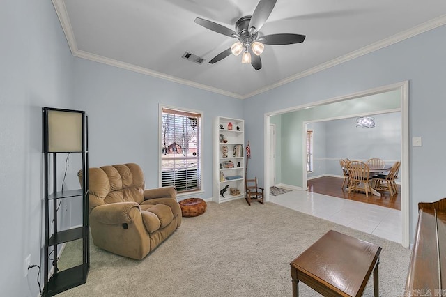 sitting room with visible vents, a ceiling fan, carpet, and ornamental molding