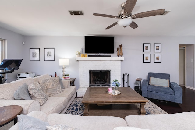 living room featuring visible vents, a ceiling fan, wood finished floors, and a fireplace