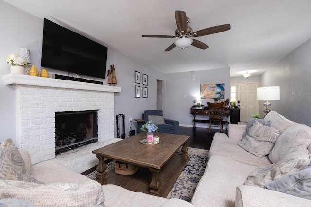 living area featuring ceiling fan, baseboards, wood finished floors, and a fireplace