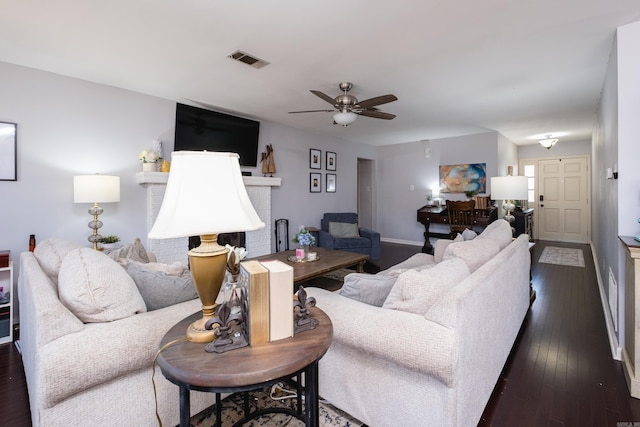 living room with visible vents, a ceiling fan, wood-type flooring, baseboards, and a brick fireplace