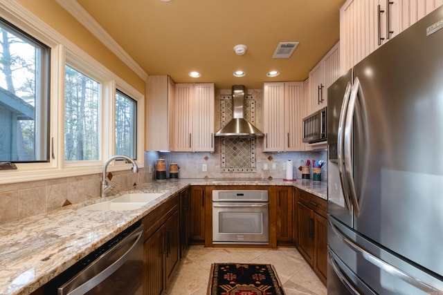 kitchen featuring light stone countertops, visible vents, a sink, appliances with stainless steel finishes, and wall chimney exhaust hood