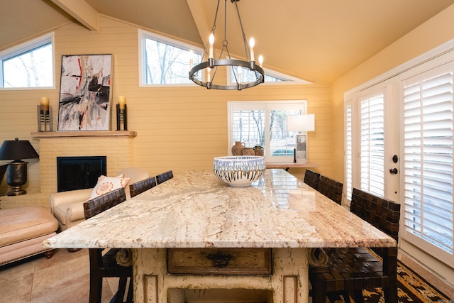 dining room featuring a chandelier, wood walls, a fireplace, and vaulted ceiling with beams