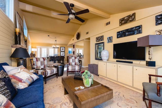 living area with lofted ceiling with beams, ceiling fan with notable chandelier, visible vents, and wood walls