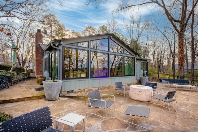 rear view of house featuring a patio, a chimney, and an outdoor fire pit