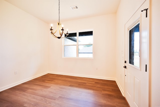 interior space with visible vents, baseboards, an inviting chandelier, and wood finished floors