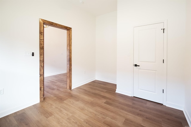 spare room with baseboards and wood finished floors