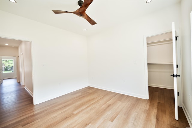 unfurnished bedroom with recessed lighting, a walk in closet, baseboards, and wood finished floors