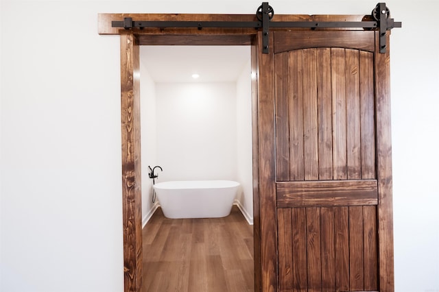 bathroom featuring wood finished floors, baseboards, and a freestanding tub