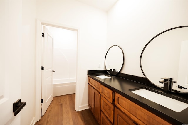 full bathroom featuring double vanity, wood finished floors, and a sink