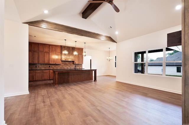 kitchen with tasteful backsplash, open floor plan, beamed ceiling, and dark countertops