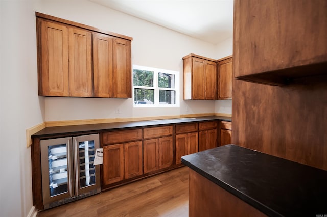 kitchen featuring beverage cooler, light wood-type flooring, and brown cabinetry