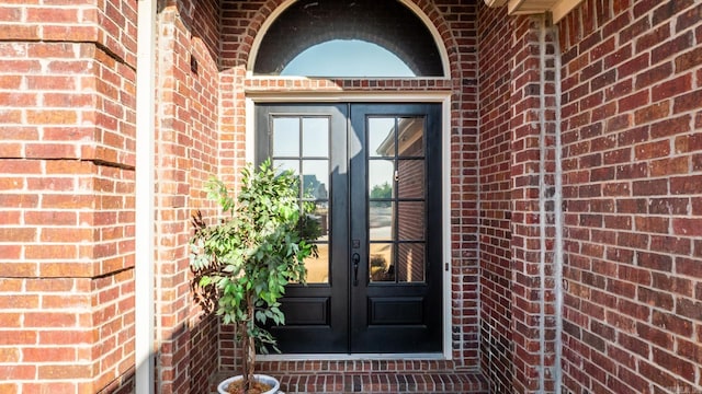 view of exterior entry featuring french doors and brick siding