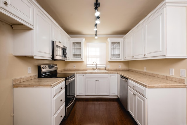 kitchen with white cabinets, appliances with stainless steel finishes, glass insert cabinets, and a sink