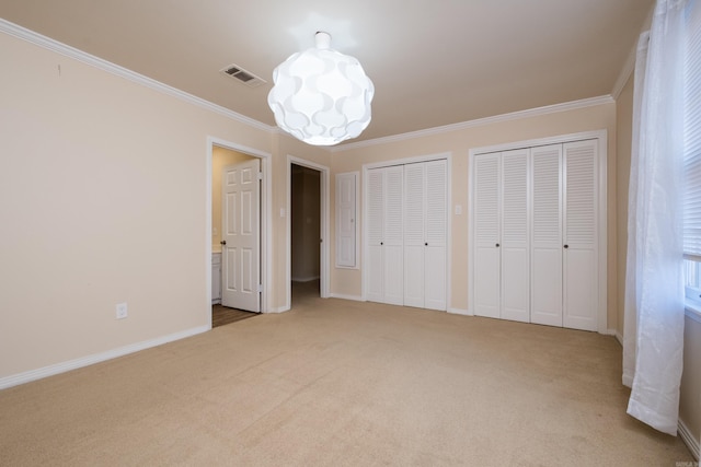 unfurnished bedroom with visible vents, baseboards, multiple closets, ornamental molding, and carpet flooring