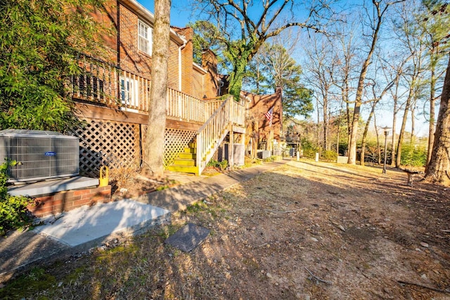 view of yard with central air condition unit, stairs, and a deck