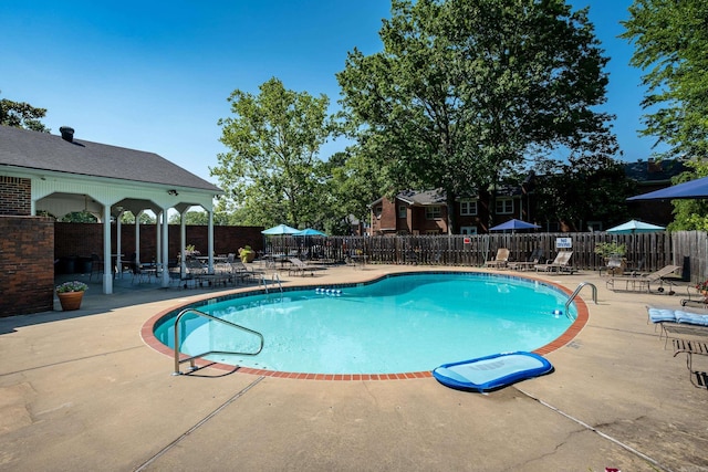 community pool with a patio and fence