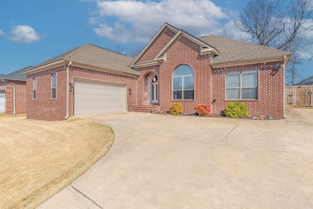 view of front of property featuring brick siding, roof with shingles, and concrete driveway