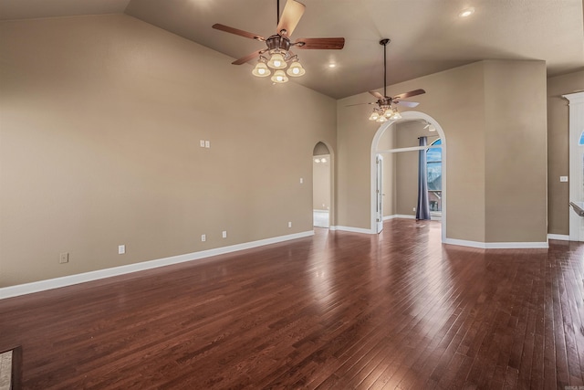 spare room featuring arched walkways, baseboards, ceiling fan, and dark wood-style flooring