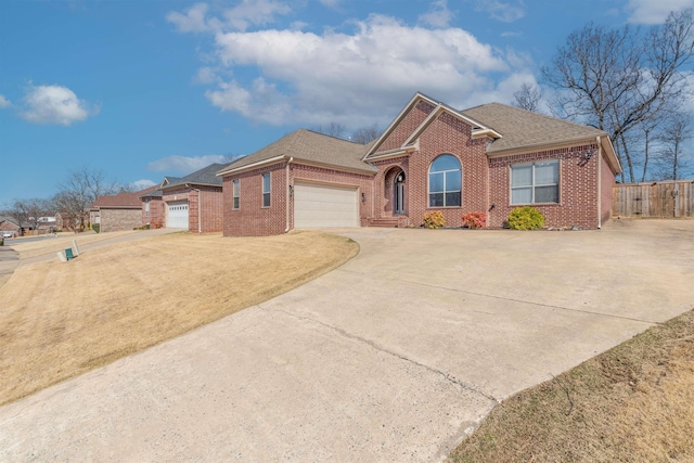 view of front of house with a garage, brick siding, driveway, and fence