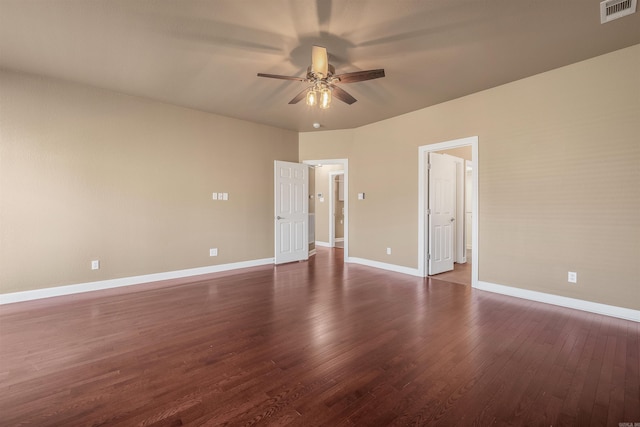 empty room featuring dark wood finished floors, visible vents, a ceiling fan, and baseboards